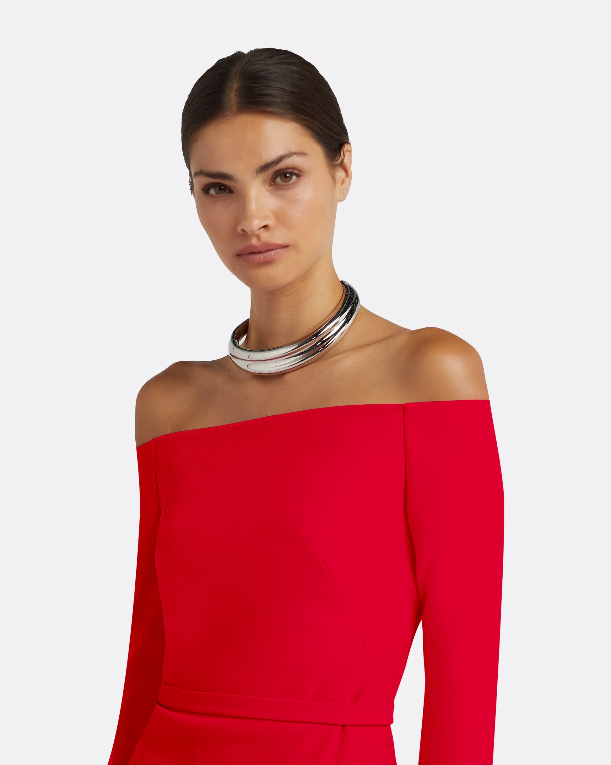Woman wearing a red off-shoulder dress with a plain background, detail view
